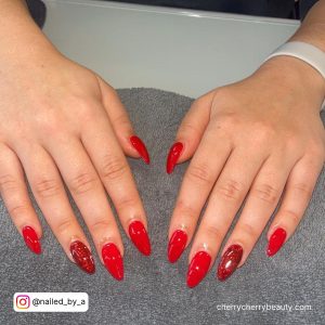 Almond Glitter Red Acrylic Nails Over Grey Clothe