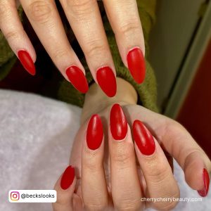 Almond Matte Red Acrylic Nails Over White Surface