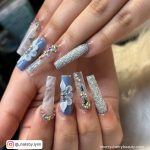 Baddie Coffin Blue Acrylic Nails With Flower And Marble Design, Rhinestones, And Glitters