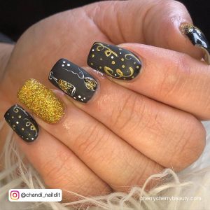 Black And Gold Acrylic Nail Designs With Glitter On Ring Finger