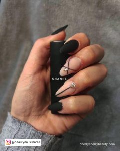Chic Black Almond Acrylic Nails With Diamonds Holding Black Polish Bottle
