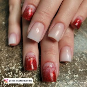 Clear And Red Glitter Tip Acrylic Nails Over Glittery Surface