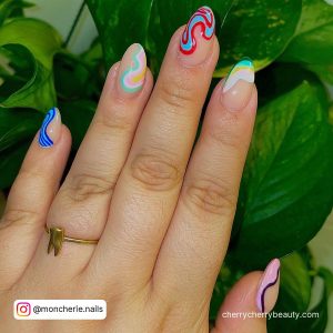 Cute Multi-Colored Acrylic Almond Nails With Green Leaves In Background