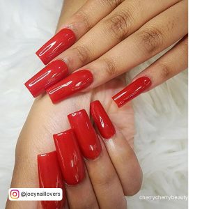 Hot Red Medium Length Square Acrylic Nails On A White Surface