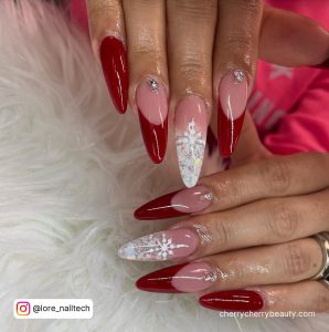 Long Almond Red Acrylic Nails With Glitter With Snowflakes Design And Diamonds Over White Fur