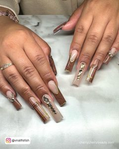 Long Baddie Coffin French Acrylic Nails With Rhinestones, Gold Glitter, Check Design, And Marble Design Over White Silk Clothe