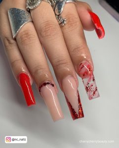 Marble Nude And Red Acrylic Nails With Glitters And Rhinestones Over White Surface