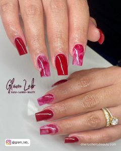 Pink And Red Marble Acrylic Nails Over White Surface