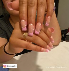 Pretty Pink French Tip Acrylic Nails With Pearls Over White Surface