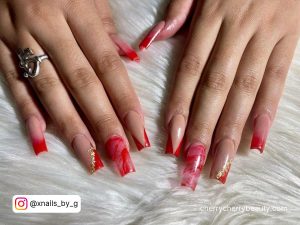 Pretty Red Acrylic Nails With Gold Flakes On White Fur