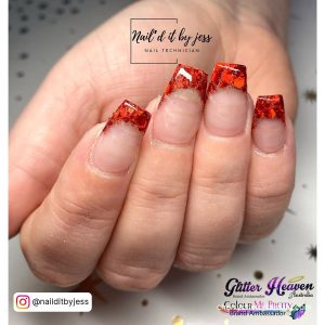 Red French Acrylic Nails With Red Flakes On White Surface