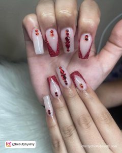 Red Valentine'S Day Acrylic Nails With Rhinestones On A White Fur Surface