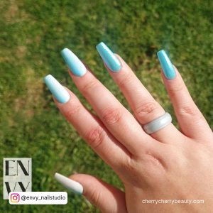 Shimmery Sky Blue Acrylic Nails With Green Grasses In Background
