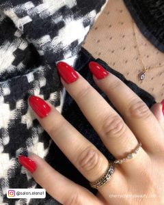 Short Almond Red Acrylic Nails Over Black And White Clothe