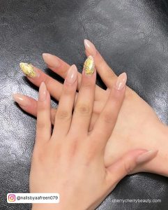 Short Stiletto Acrylic Almond Nails With Gold Flakes On Black Surface