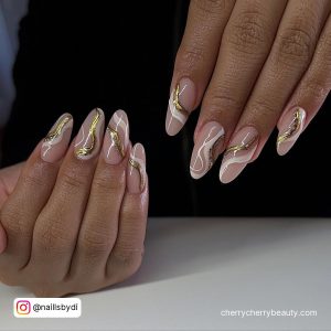 Swirly Gold White Acrylic Almond Nails Over White Surface