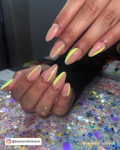 Tropical Yellow And Nude Almond Acrylic Nails Over Glittery Surface